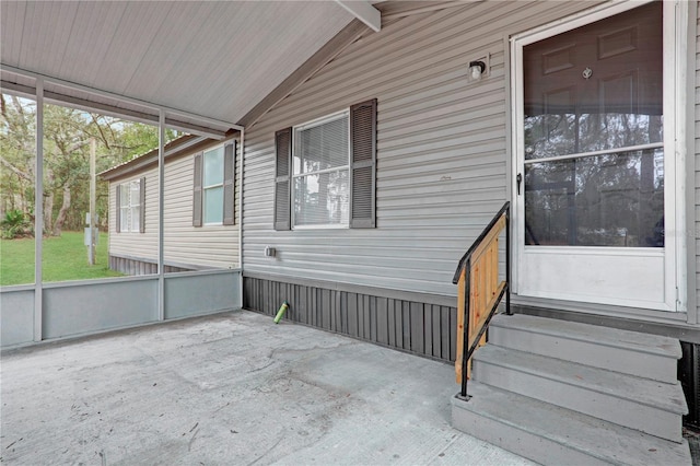 unfurnished sunroom featuring lofted ceiling with beams and a wealth of natural light