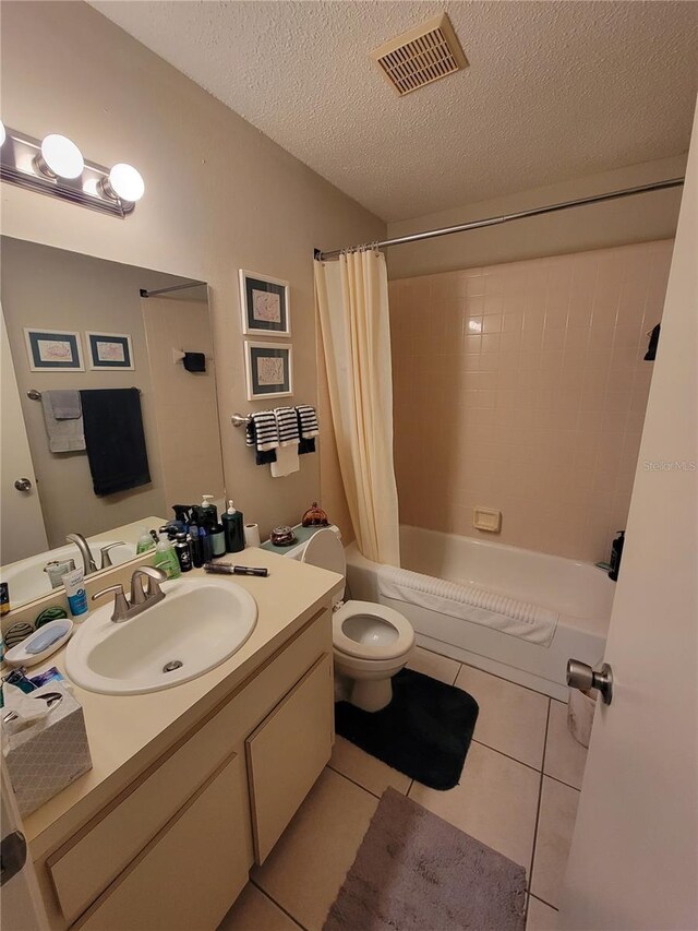 full bathroom featuring tile patterned floors, vanity, a textured ceiling, shower / bath combo with shower curtain, and toilet