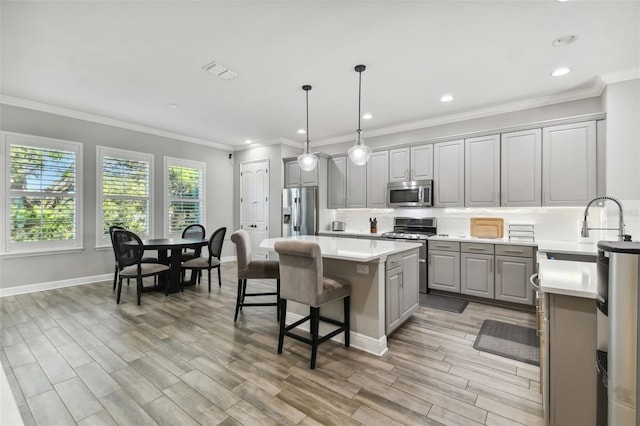 kitchen featuring sink, gray cabinets, decorative light fixtures, a kitchen island, and stainless steel appliances