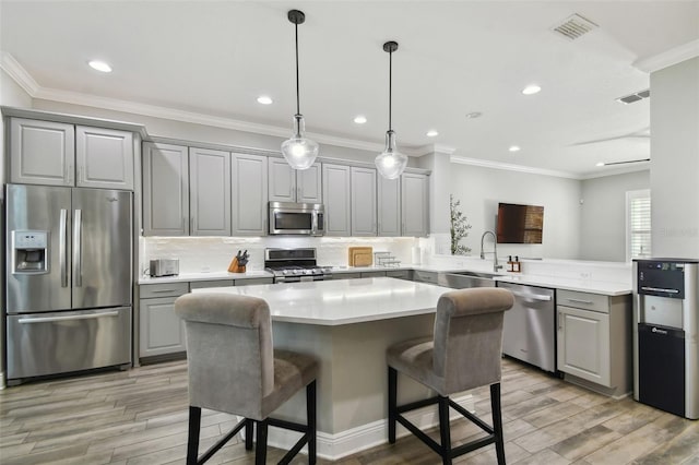 kitchen featuring sink, stainless steel appliances, kitchen peninsula, a kitchen bar, and gray cabinets