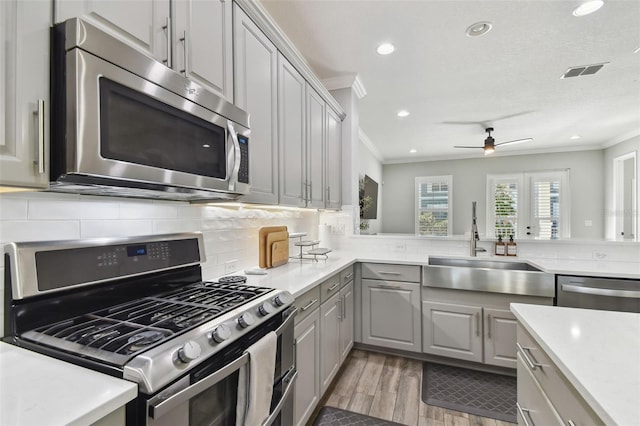 kitchen with tasteful backsplash, gray cabinets, stainless steel appliances, and ornamental molding