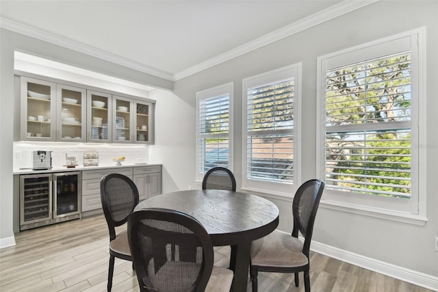 dining room featuring wine cooler, light hardwood / wood-style floors, and ornamental molding