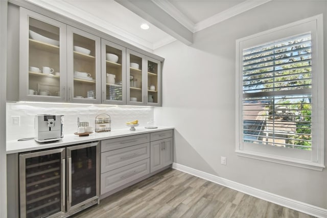 bar with tasteful backsplash, ornamental molding, beverage cooler, beamed ceiling, and gray cabinets