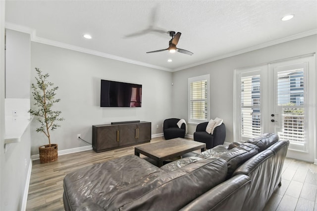 living room with ceiling fan, french doors, light hardwood / wood-style flooring, a textured ceiling, and ornamental molding