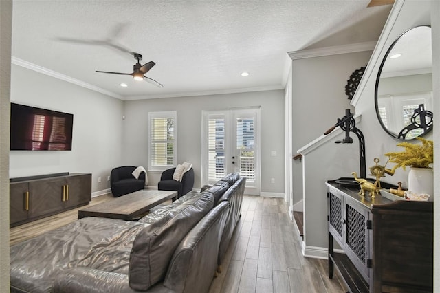 living room with a textured ceiling, ceiling fan, wood-type flooring, and crown molding