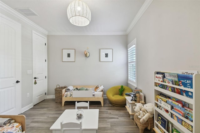 recreation room featuring hardwood / wood-style floors and ornamental molding