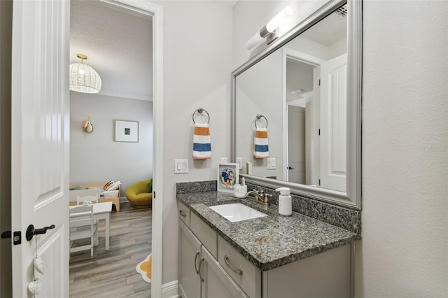 bathroom with crown molding, hardwood / wood-style floors, and vanity