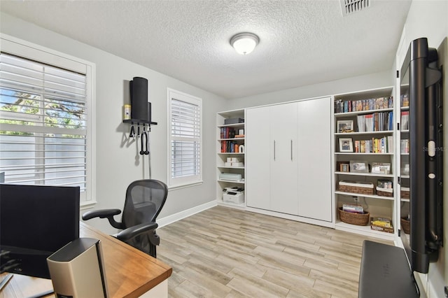 home office with a textured ceiling, light wood-type flooring, and plenty of natural light