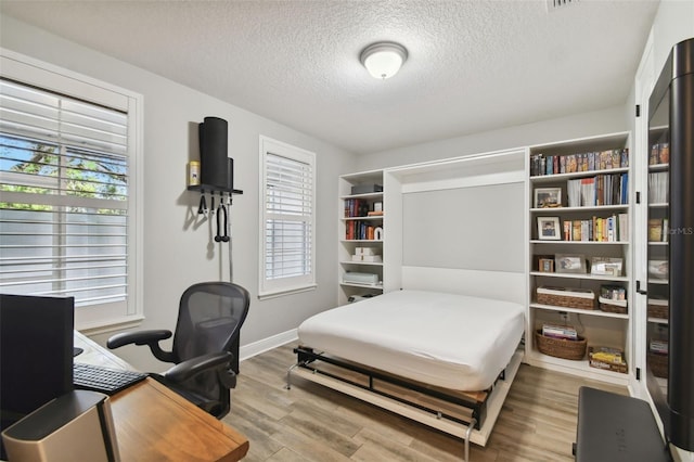 bedroom with a textured ceiling and light hardwood / wood-style flooring