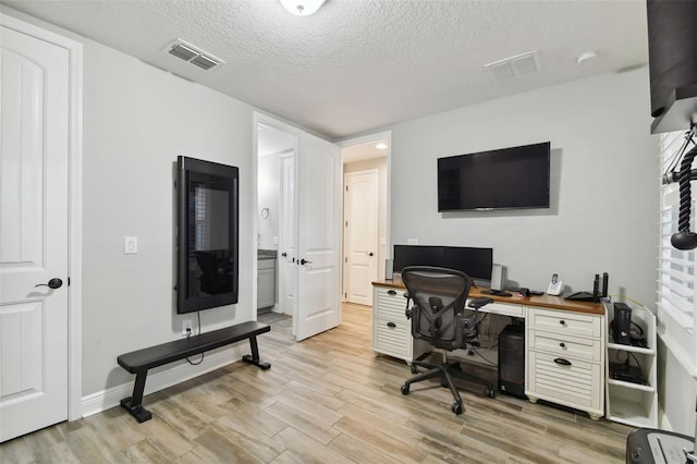 office with light wood-type flooring and a textured ceiling