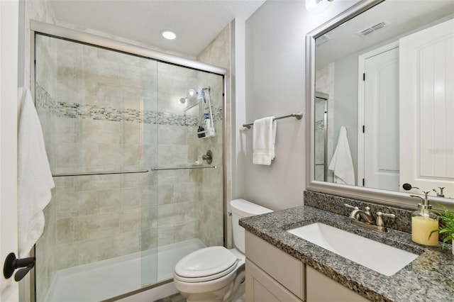 bathroom featuring vanity, a shower with shower door, and toilet