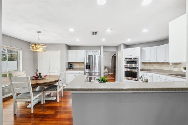 kitchen with white cabinets, pendant lighting, stainless steel appliances, and tasteful backsplash