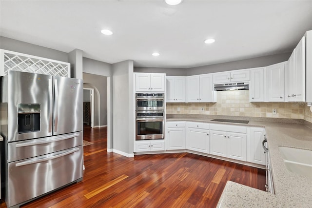 kitchen featuring appliances with stainless steel finishes, tasteful backsplash, light stone counters, dark wood-type flooring, and white cabinetry