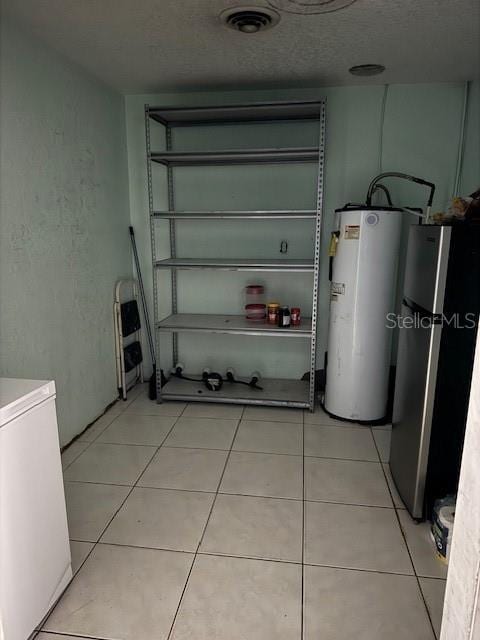 garage with washer / dryer, stainless steel refrigerator, and water heater