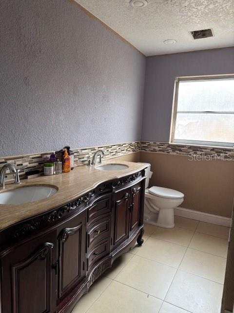 bathroom with tile patterned floors, vanity, toilet, and a textured ceiling