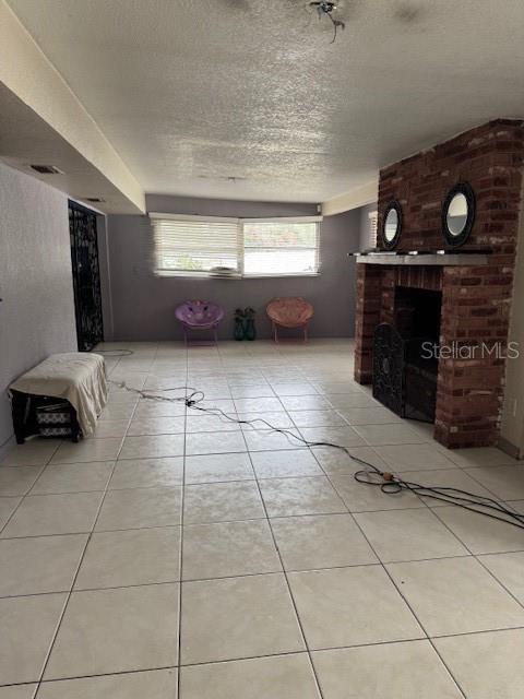 unfurnished living room with a fireplace, a textured ceiling, and light tile patterned flooring