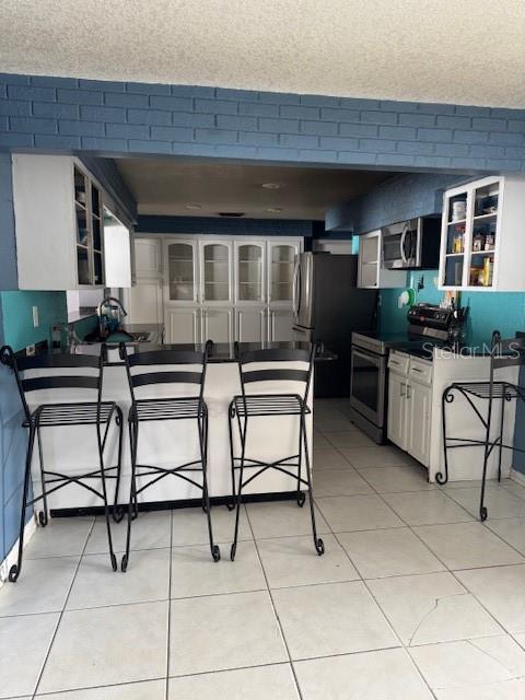 kitchen featuring white cabinets, a breakfast bar, stainless steel appliances, and light tile patterned flooring