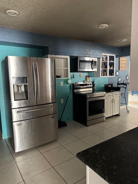 kitchen with white cabinets, light tile patterned flooring, and appliances with stainless steel finishes