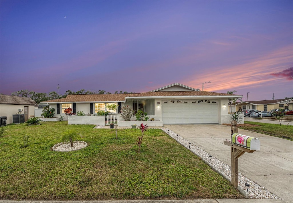 single story home with a yard, cooling unit, and a garage