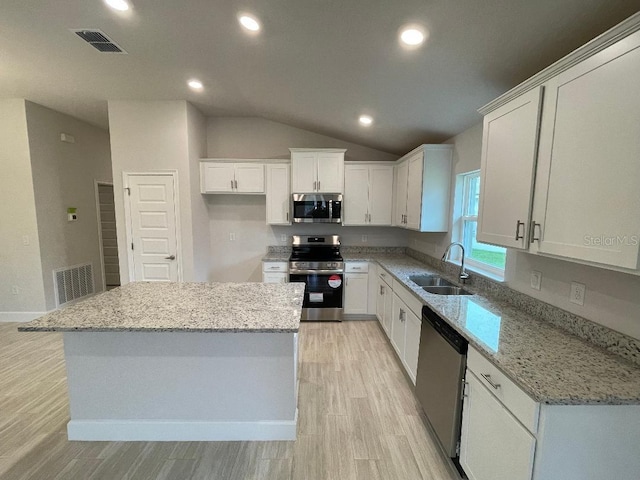 kitchen featuring sink, light stone countertops, a kitchen island, white cabinetry, and stainless steel appliances