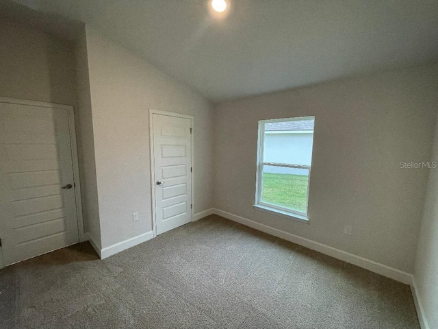 unfurnished bedroom featuring carpet flooring, vaulted ceiling, and a closet