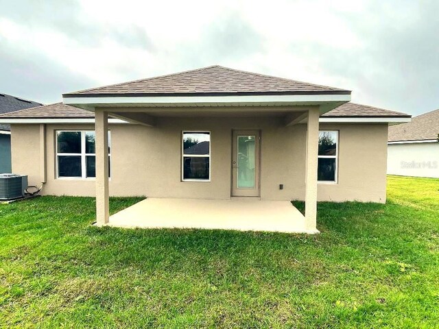 back of house featuring cooling unit, a yard, and a patio