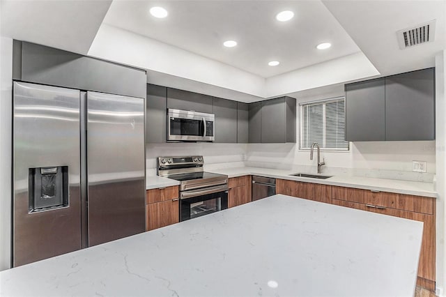 kitchen featuring light stone counters, sink, and appliances with stainless steel finishes