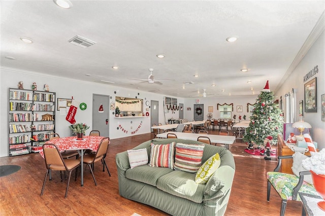 living room with wood-type flooring, ornamental molding, and ceiling fan