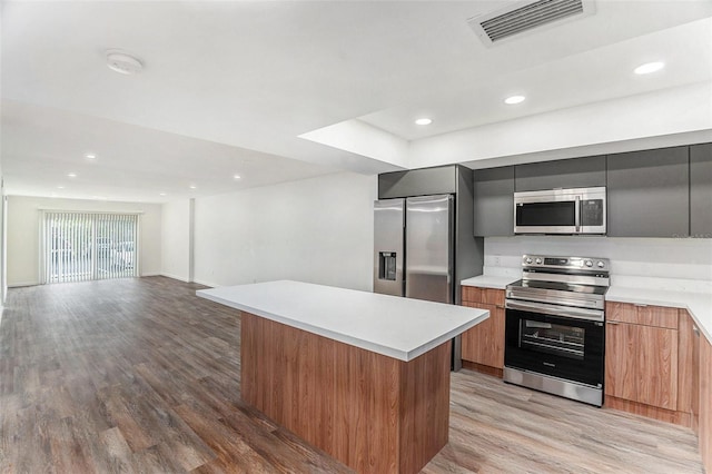 kitchen with light hardwood / wood-style flooring, a kitchen island, and appliances with stainless steel finishes