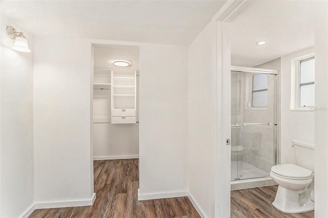 bathroom featuring toilet, a shower with shower door, and hardwood / wood-style floors