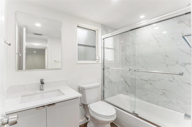 full bathroom featuring vanity, bath / shower combo with glass door, and toilet