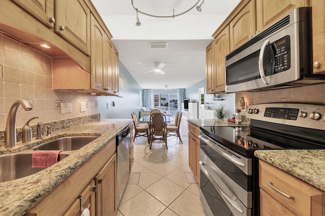 kitchen with light stone countertops, stainless steel appliances, sink, light tile patterned floors, and light brown cabinets