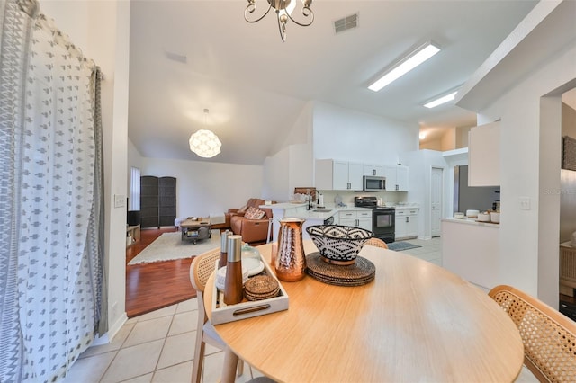 dining space featuring vaulted ceiling, light tile patterned floors, and a chandelier