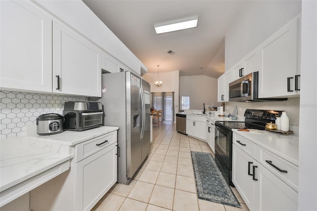 kitchen featuring appliances with stainless steel finishes, vaulted ceiling, light tile patterned floors, pendant lighting, and white cabinets