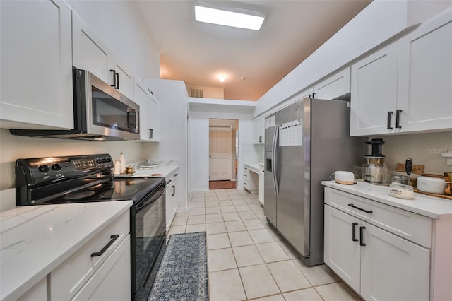 kitchen with light tile patterned flooring, light stone countertops, white cabinetry, and appliances with stainless steel finishes