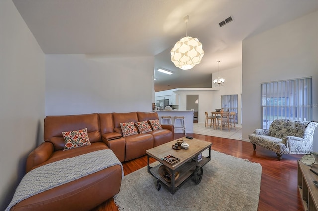 living room featuring an inviting chandelier, vaulted ceiling, and hardwood / wood-style flooring