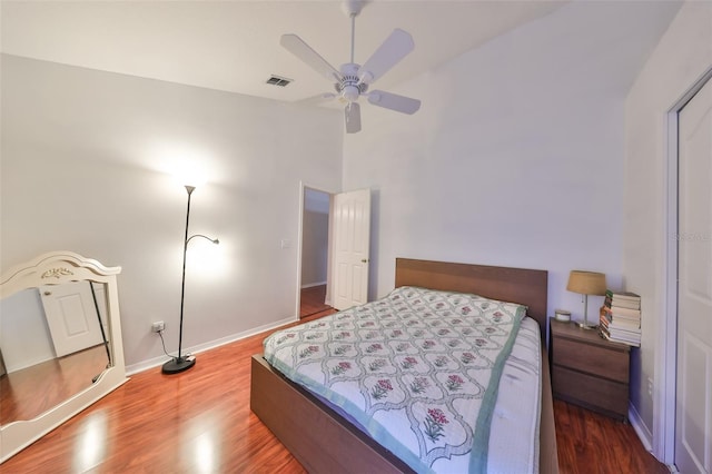 bedroom featuring ceiling fan, hardwood / wood-style floors, and a towering ceiling