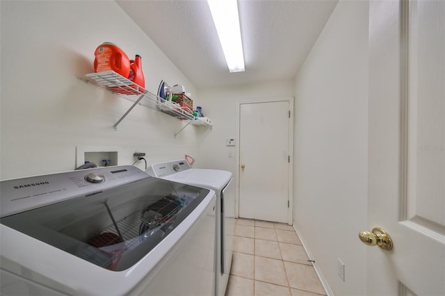 laundry room featuring light tile patterned flooring, washing machine and dryer, and a textured ceiling