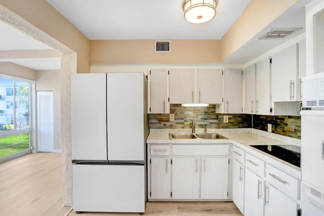 kitchen featuring white cabinets, white fridge, black electric cooktop, and sink