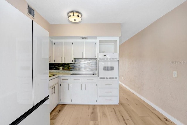 kitchen with decorative backsplash, white appliances, light hardwood / wood-style floors, and white cabinetry