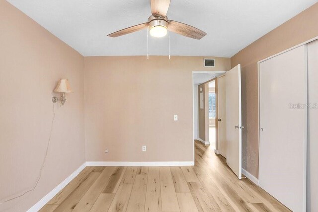 unfurnished bedroom featuring light wood-type flooring, a closet, and ceiling fan