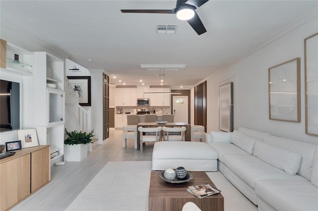 living room with ceiling fan and ornamental molding