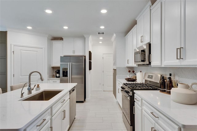 kitchen featuring white cabinets, stainless steel appliances, a kitchen island with sink, and sink