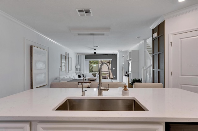 kitchen with white cabinets, crown molding, sink, ceiling fan, and light stone countertops