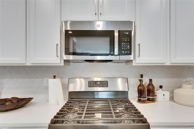 kitchen with decorative backsplash, white cabinetry, and appliances with stainless steel finishes