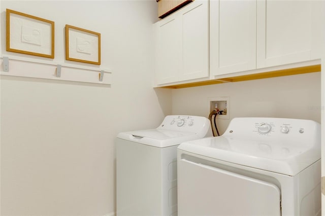 clothes washing area with separate washer and dryer and cabinets