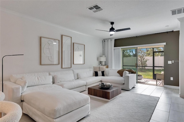 tiled living room with ceiling fan, a textured ceiling, and ornamental molding