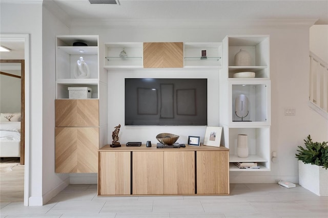 interior space featuring built in shelves, light brown cabinetry, and crown molding