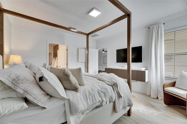 bedroom with light hardwood / wood-style flooring, a textured ceiling, and ornamental molding