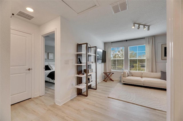 interior space with rail lighting, light hardwood / wood-style floors, and a textured ceiling